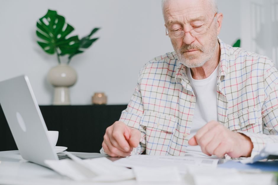 A Navy veteran reviewing asbestos exposure benefits paperwork at his kitchen table